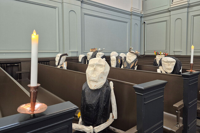 Kirkon penkissä istuu 12 puhlasuihin pukeutunutta kuolemahahmoa.